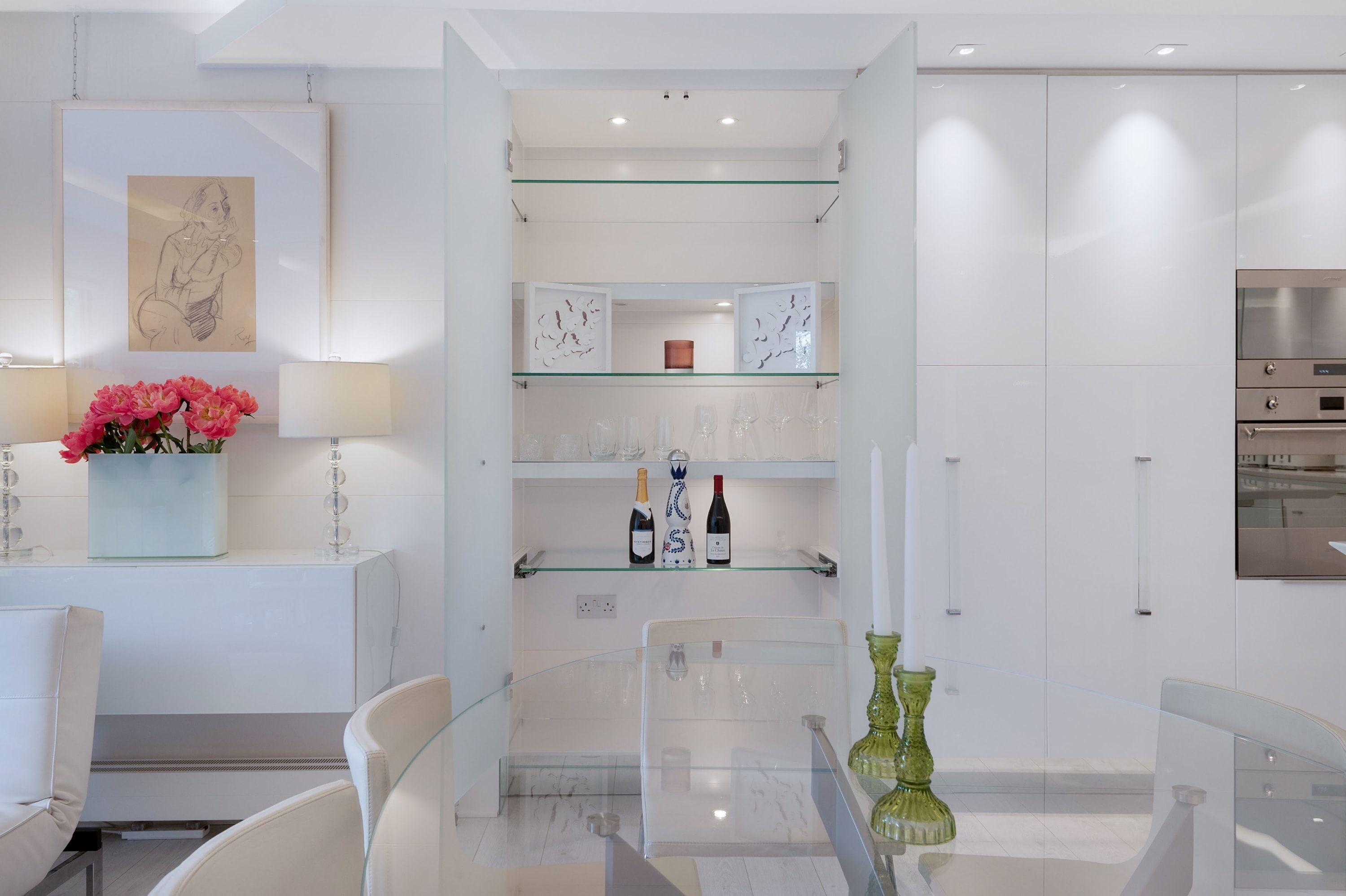 A modern kitchen with glass shelves, a dining table, and a large oven.