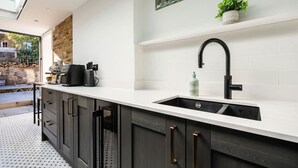 A modern kitchen with a white countertop, dark cabinetry, and a black faucet. - The Blooming Minimalist- by Out of Office Lifestyle (London)