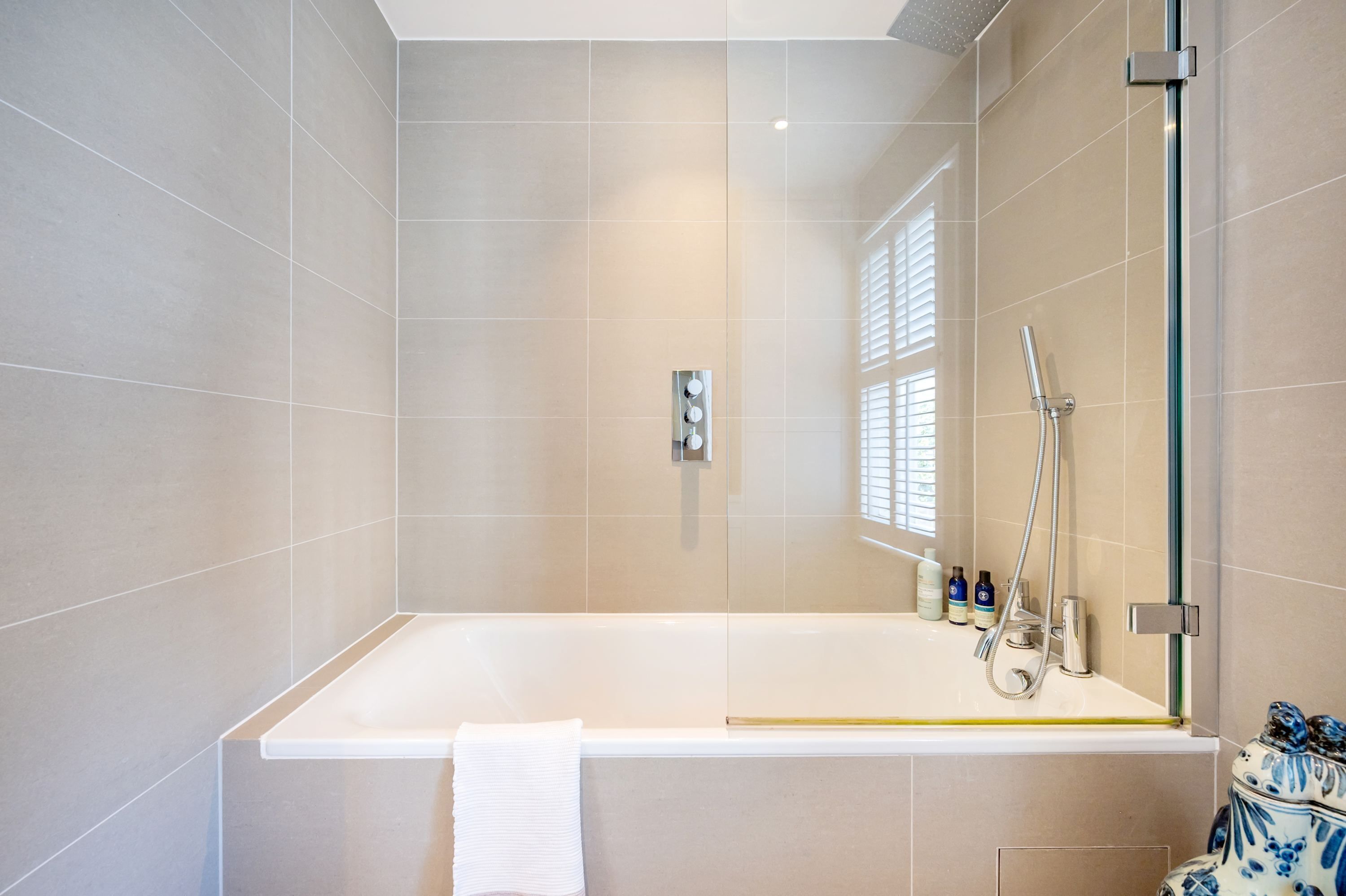 A modern bathroom with a bathtub, shower, and a glass-enclosed shower area.