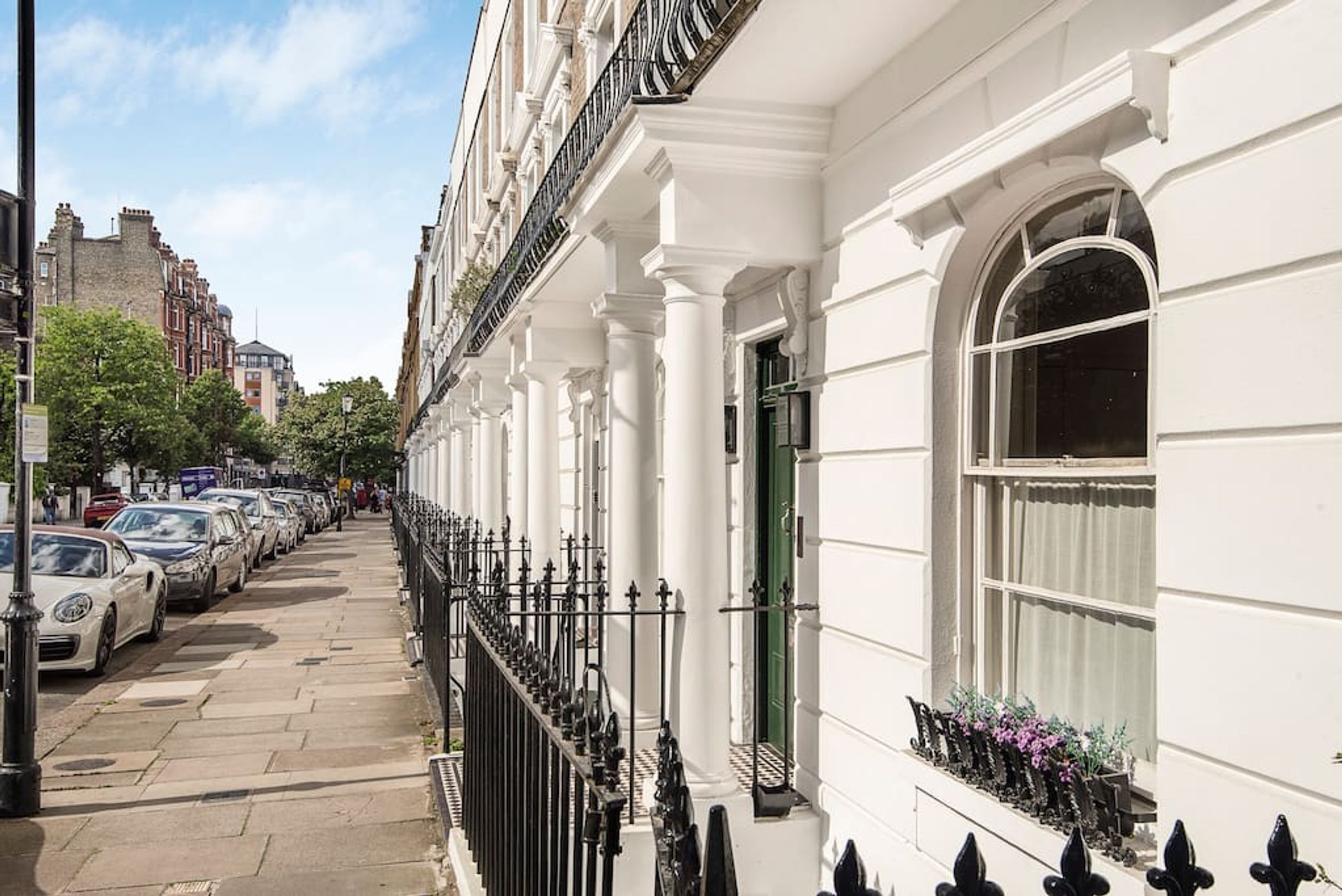 A row of white buildings with black iron railings and a green door.