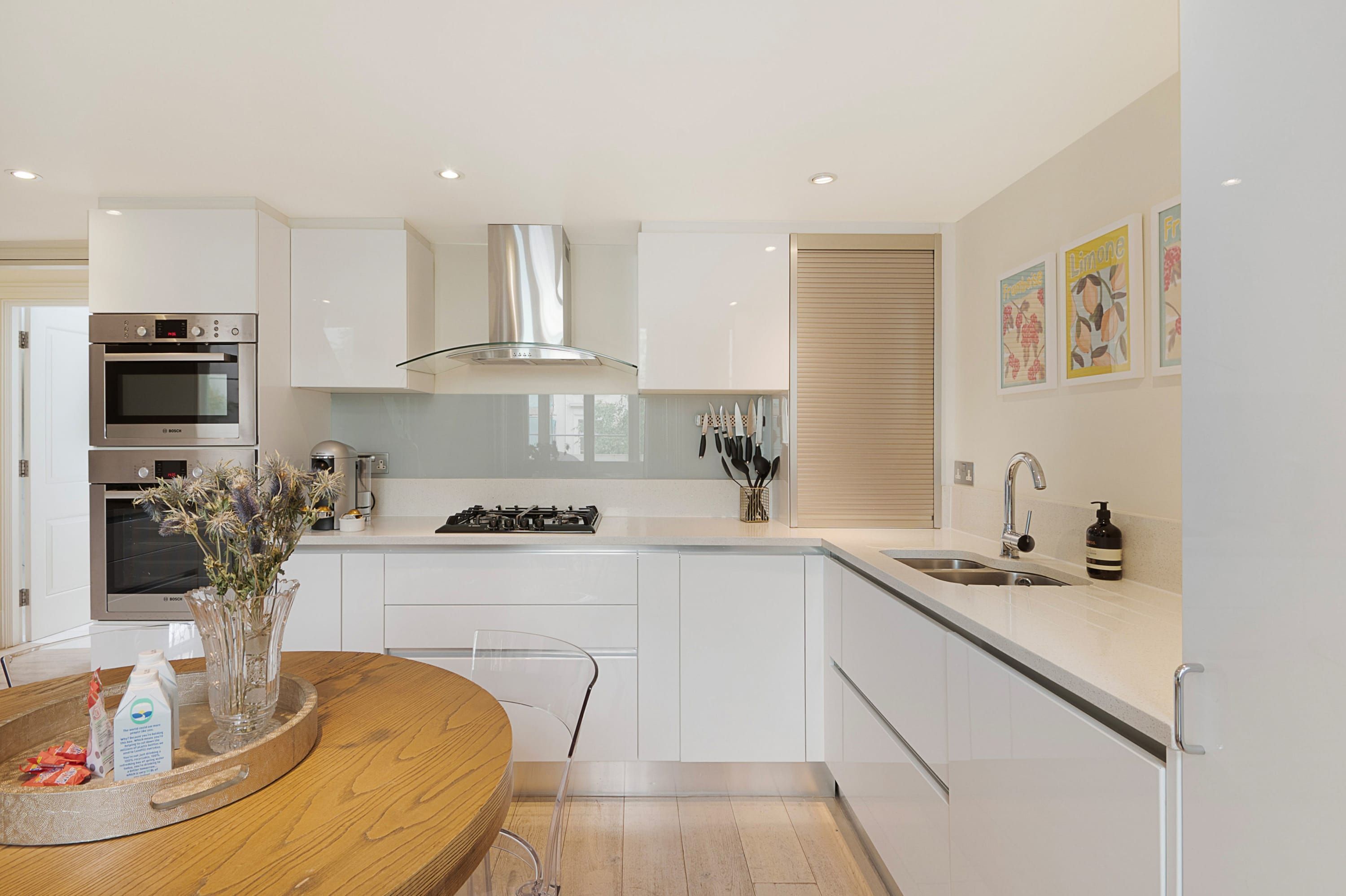 A modern kitchen with white cabinetry, stainless steel appliances, and a central island with a vase of flowers.