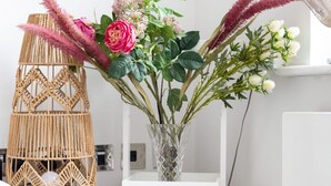 Une étagère blanche avec un vase de fleurs et un panier en osier.