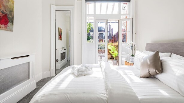 Ein Hotelzimmer mit einem Bett, einem Heizkörper, einer Tür, die auf einen Balkon führt, und einem Gemälde an der Wand.