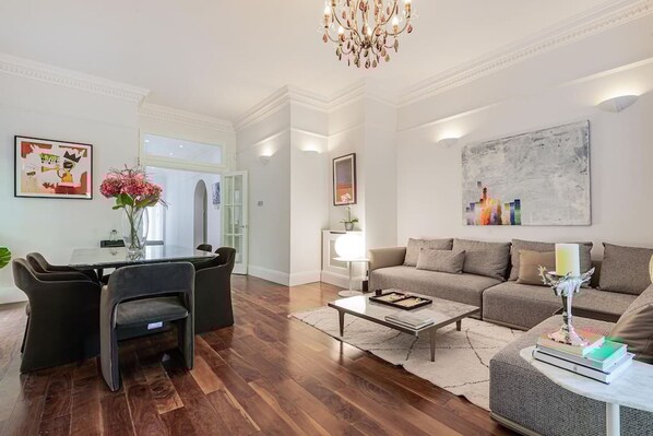 A modern living room with a dining area, a chandelier, and artwork on the walls. - The Family Getaway - by Out of Office Lifestyle (London)