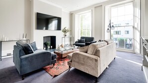 A modern living room with a large TV, a fireplace, and a balcony with a view.