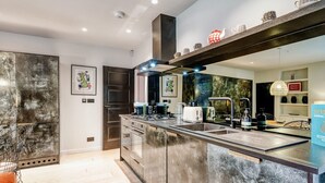A modern kitchen with a large island, stainless steel appliances, and a hanging light fixture. - Notting Hill 2 Bed With Sauna - by Out of Office Lifestyle (London)