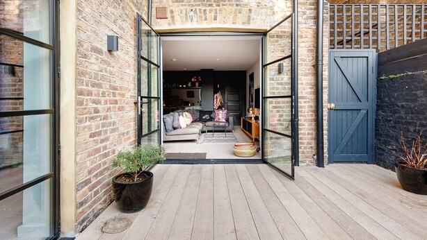 An open doorway leading to a living area with a sofa, cushions, and a small table. - Notting Hill 2 Bed With Sauna - by Out of Office Lifestyle (London)