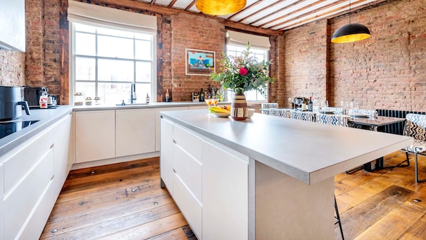 A spacious kitchen with a large island, wooden beams, brick walls, and a view through large windows. - Long Term Stay- Notting Hill by Out of Office Lifestyle (London)