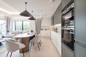 A modern kitchen with a central island, white cabinetry, and built-in appliances. - The Modern Glasshouse - by Out of Office Lifestyle (London)