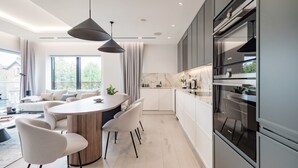 A modern kitchen with a central island, white cabinetry, and built-in appliances.