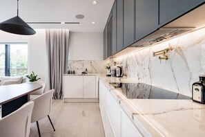Een moderne keuken met marmeren aanrecht, een inbouwfornuis en een hanglamp.