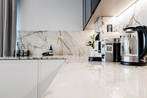 A modern kitchen with a marble backsplash, a coffee maker, and a kettle. - The Modern Glasshouse - by Out of Office Lifestyle (London)