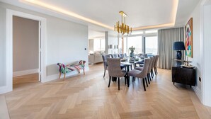 A modern dining area with a large table, chairs, and a chandelier. - Regents Park Penthouse (London)