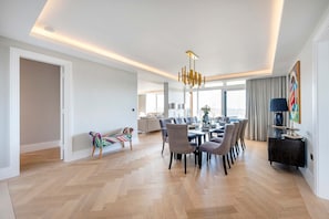 Un espace de salle à manger moderne, doté d’une grande table, de chaises et d’un lustre.