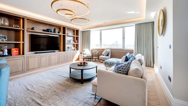 A modern living room with a large TV, wooden shelving, a round coffee table, and a sofa. - Regents Park Penthouse (London)