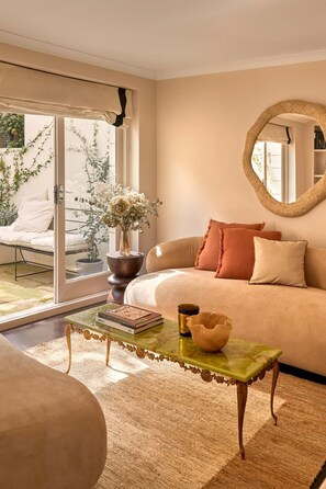 Ein gemütliches Wohnzimmer mit einer Couch, einem Couchtisch und einem großen Fenster mit Blick auf einen Garten.