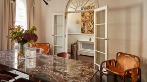 Un comedor con una mesa de mármol, sillas y un jarrón con flores.
