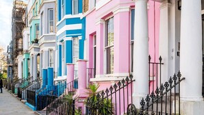 Una hilera de casas coloridas en terrazas, con columnas blancas y barandillas de hierro forjado negro.