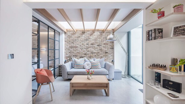 Una sala de estar moderna con una pared de ladrillo, un sofá, una mesa de centro y una estantería.