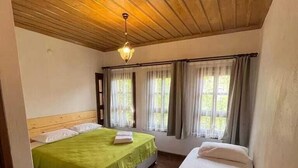 A room with two beds, wooden ceiling, and large windows with curtains. - Trilye Taşev (Mudanya)
