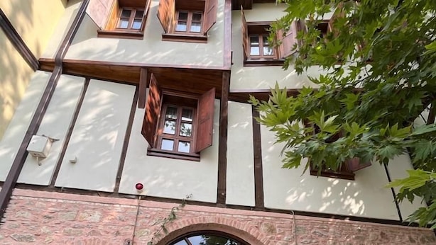 A traditional building with a stone facade, wooden shutters, and a central entrance with a large wooden door. - Trilye Taşev (Mudanya)