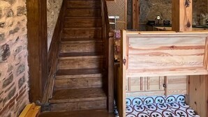A wooden staircase leading to a room with a patterned floor and a wooden bed frame. - Trilye Taşev (Mudanya)