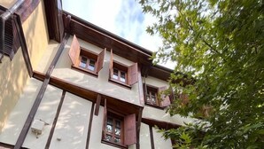 A traditional building with a stone facade, wooden shutters, and a central arched entrance. - Trilye Taşev (Mudanya)