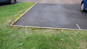 Ein Parkplatz mit befestigter Fahrbahnoberfläche und einer Rasengrenze.