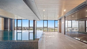 A modern indoor swimming pool with large windows offering city views. - Heart of Southbank, Walk to Crown, Resort style amenities & Free Carpark (Southbank)