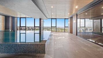 A modern indoor swimming pool with large windows offering city views.