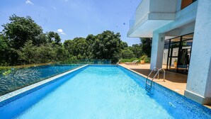 A rectangular swimming pool with a clear blue water surface, surrounded by a wooden deck and a glass railing. - Riverbank 1-bedroom apartment in terrific Nairobi Pool & Gym (Nairobi)