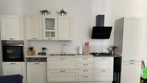A modern kitchen with white cabinets, a black oven, a gas stove, and a black range hood.