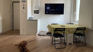 A dining area with a table, chairs, and a TV mounted on the wall.
