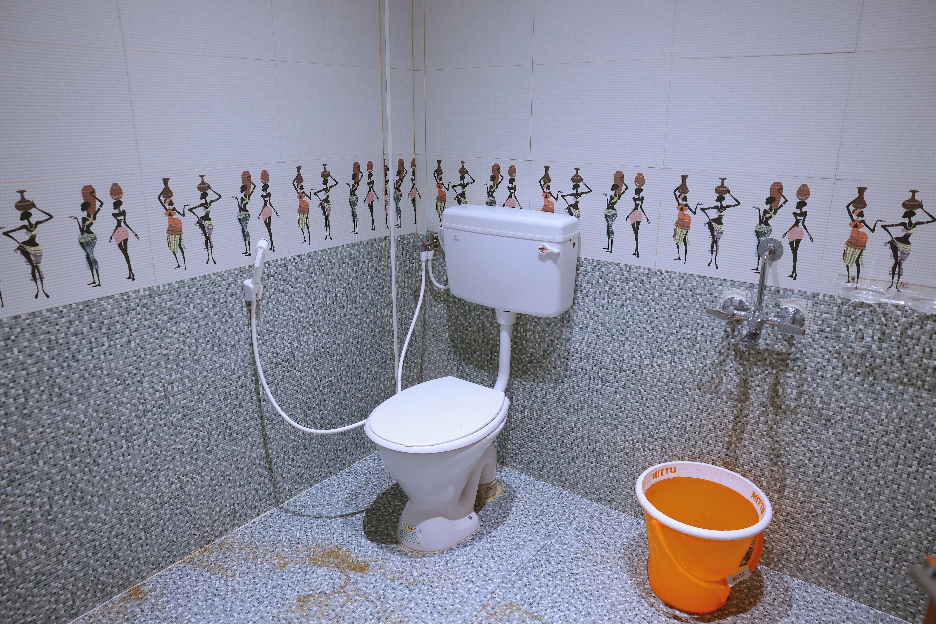 Une salle de bain équipée de toilettes, d’une douche et d’un seau.