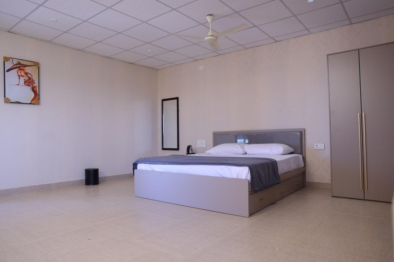 Ein Schlafzimmer mit Bett, Deckenventilator, Kleiderschrank und einem gerahmten Bild an der Wand.