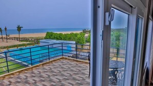 Een balkon met uitzicht op een strand en een zwembad.