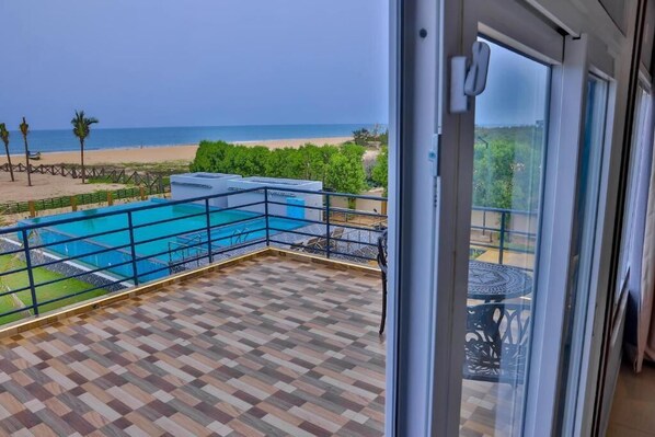 En balkon med udsigt over strand og pool.