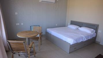 A bedroom with a bed, a table, and two chairs.