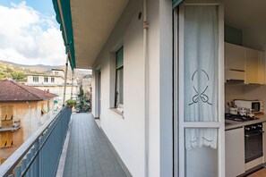 Ein schmaler Balkon mit Blick auf angrenzende Gebäude und einem Küchenbereich mit Herd und Schränken.