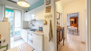 A kitchen with white cabinets, a stove, and a sink. There is a dining area with a table and chairs. - Stylish flat balcony near Rapallo Castle (Rapallo)