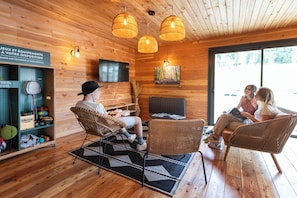 Un interior de madera con muebles de mimbre, un televisor y un cartel en francés.