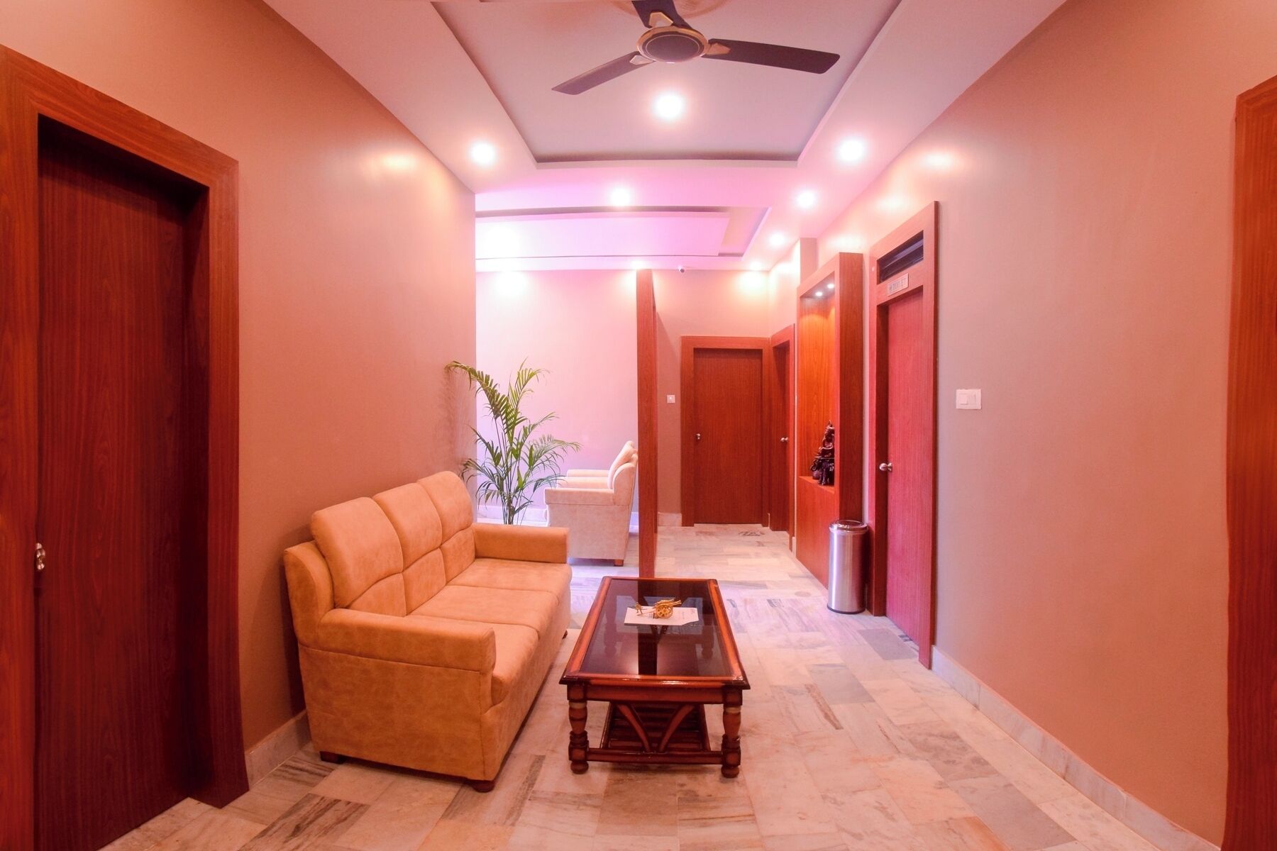 Un couloir avec un canapé, une table basse et un ventilateur de plafond.
