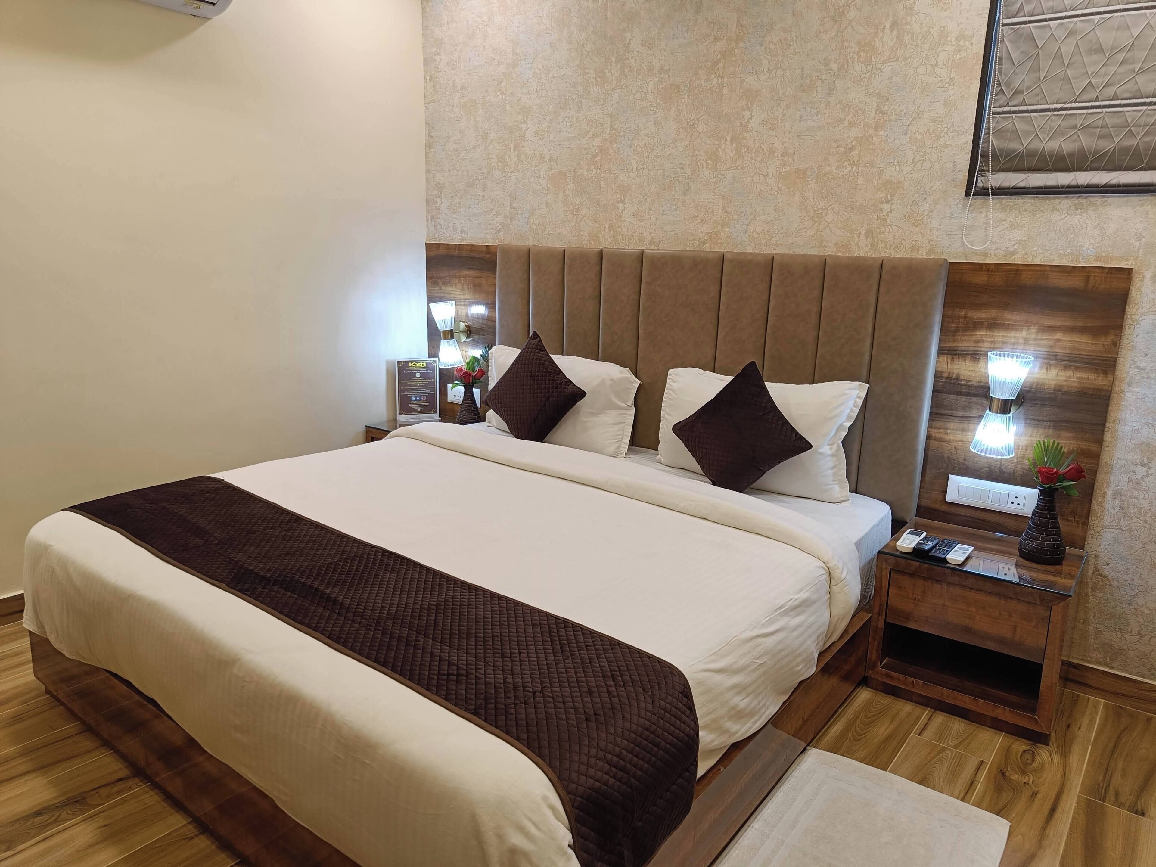 A neatly made bed with a brown quilted headboard, a bedside table with a lamp, and a small vase with a flower.