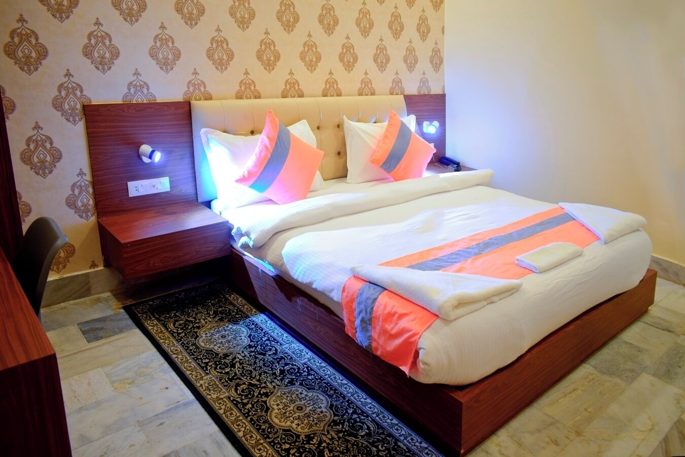 Un lit bien fait, avec une couvre-lit à motifs, une tête de lit en bois et des lampes de chevet.