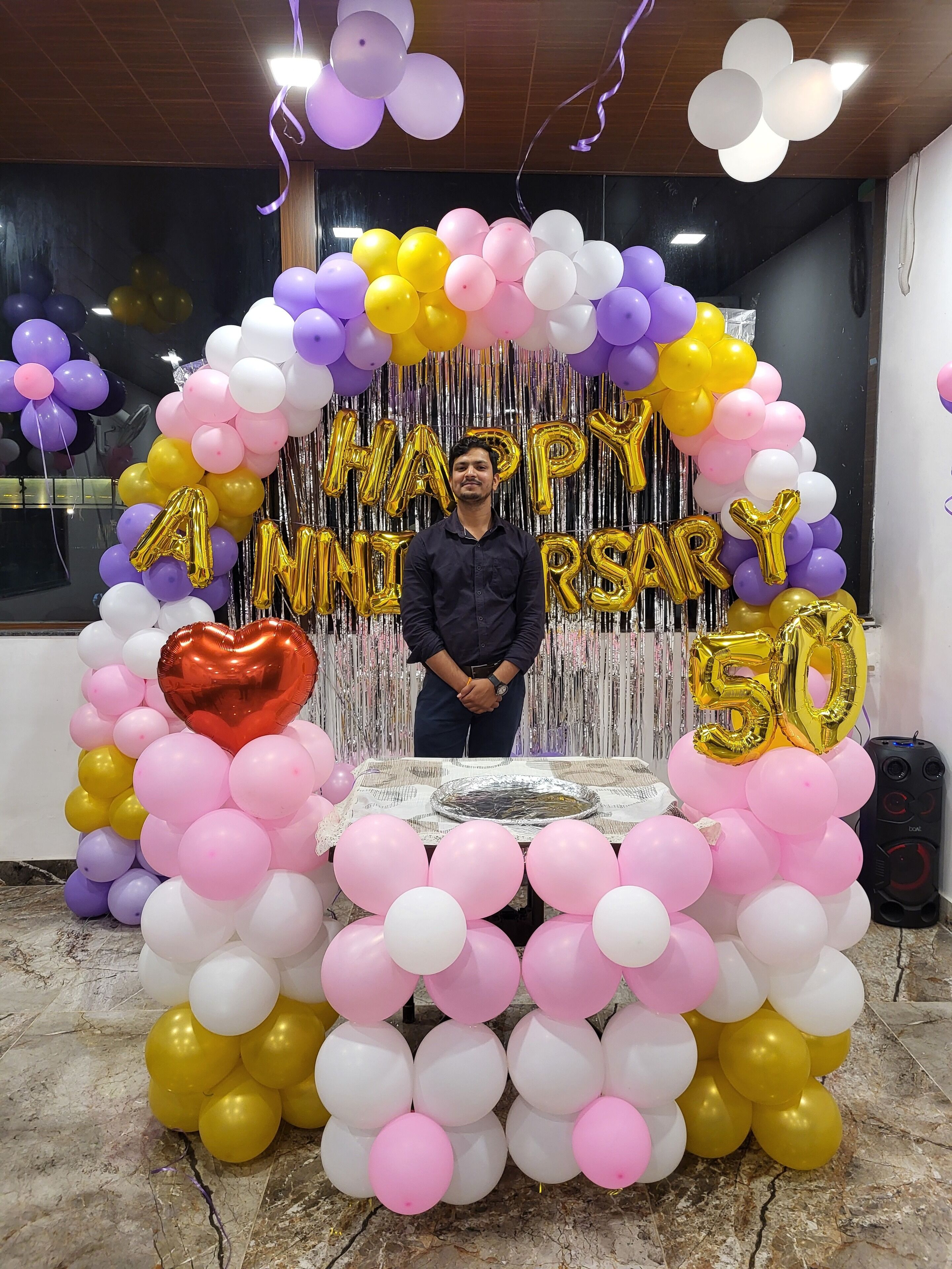 Una habitación decorada festivamente para una celebración por el 50 aniversario, con globos y serpentinas metálicas.