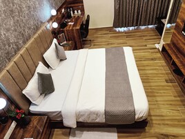Quarto de hotel bem arrumado, com uma cama grande, mesas de cabeceira, escrivaninha e uma cadeira.