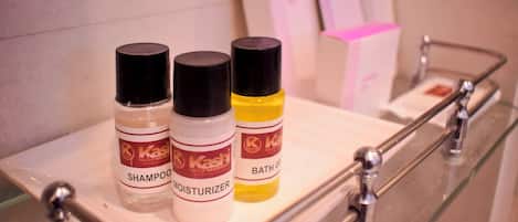 A bathroom shelf with three bottles of Kashi products: shampoo, moisturizer, and bath gel.