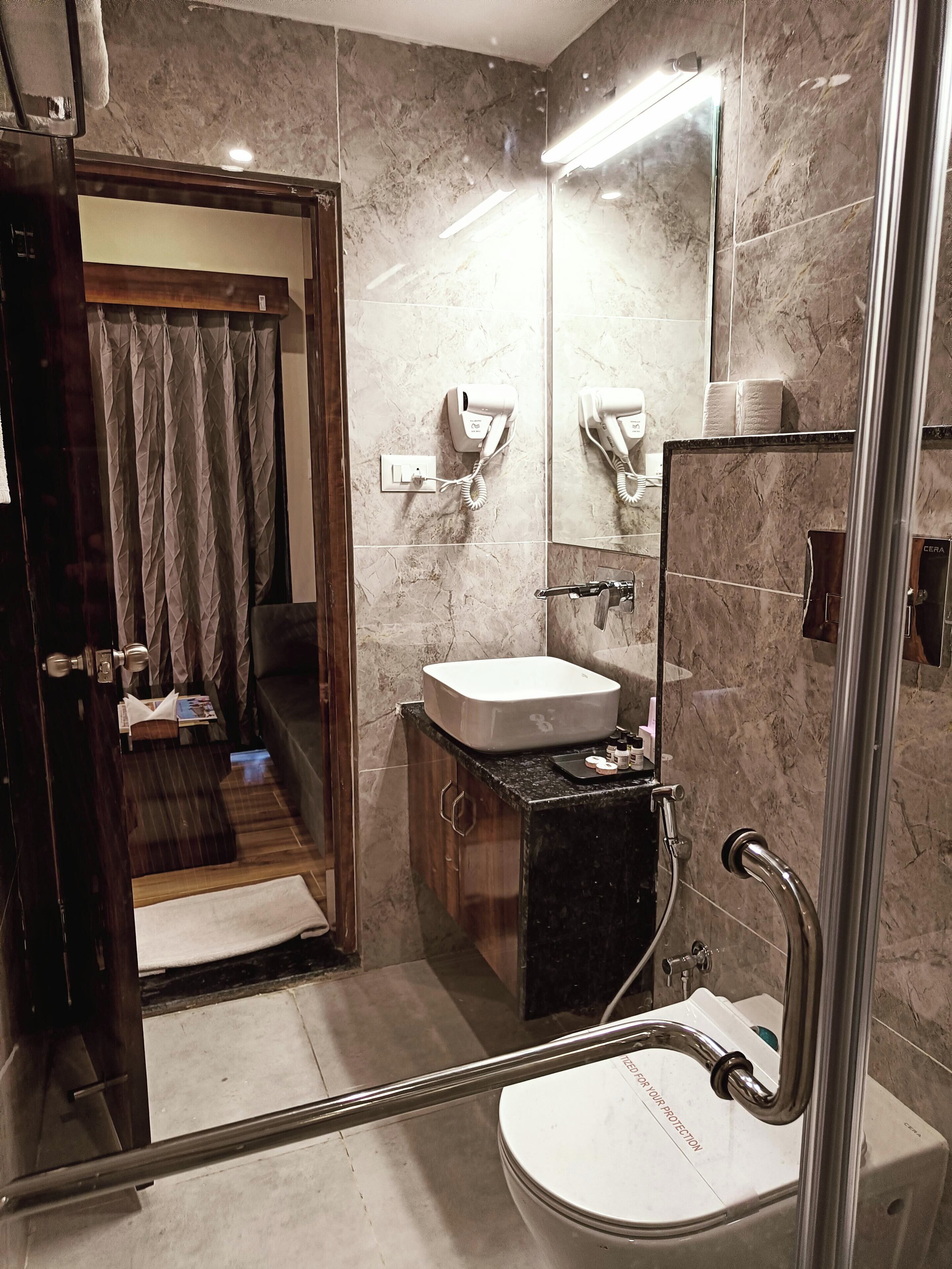 A modern bathroom with a glass shower enclosure, a white sink, and a marble-tiled wall.