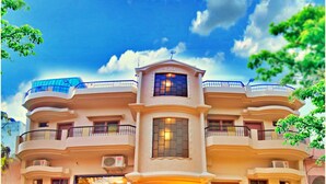A multi-story building with a central entrance, balconies, and potted plants in front. - THE KASHI RESIDENCY  (Varanasi)