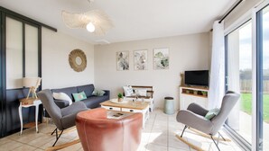 Un salon moderne comprenant un canapé, deux fauteuils à bascule, une table basse et un téléviseur.